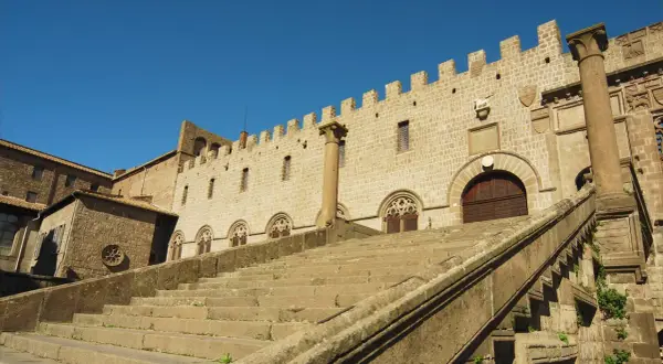 Imponente scalinata conduce al Palazzo dei Papi, parte del duomo di Viterbo, con finestre gotiche e merlature.