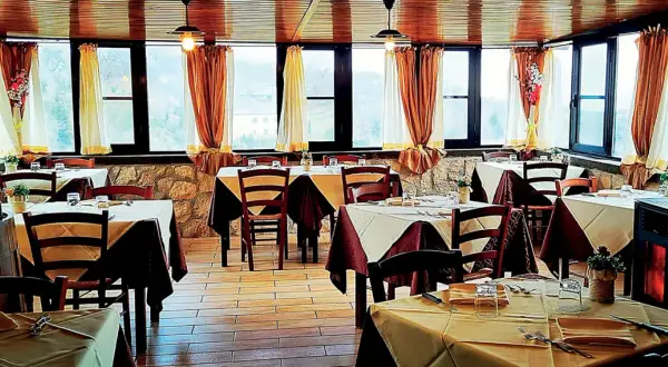 Interno di un'antica cantina a Caprarola, con tavoli apparecchiati e vista panoramica.
