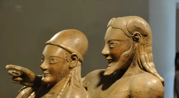 Coppia di statue in terracotta, parte di corredi funerari etruschi. Un uomo indica qualcosa, la donna lo guarda con un sorriso.