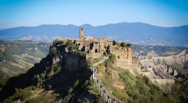 Antica città arroccata su una rupe, con un ponte pedonale che conduce al borgo. Paesaggio mozzafiato di Calcata e dintorni.
