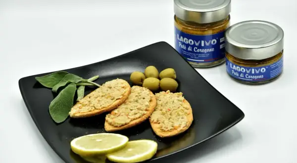 Bruschette con paté di coregone bolsena, olive verdi, limone e salvia. Due vasetti di paté di coregone in primo piano.