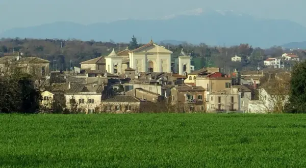 Paesaggio di Gallese, borgo vicino Viterbo, con case e una chiesa imponente, sullo sfondo montagne.