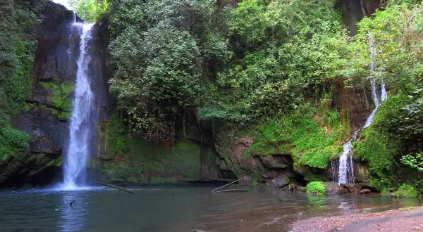 La cascata del picchio scende maestosa tra rocce ricoperte di muschio e vegetazione lussureggiante, creando un'oasi di pace.
