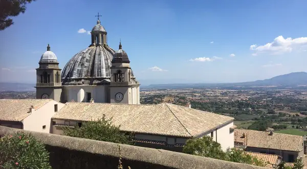 La Rocca dei Papi domina un paesaggio collinare sotto un cielo azzurro.