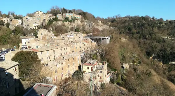 Borgo antico su una collina, con case in pietra e tetti rossi. La **Calcata storia** si svela in questo panorama.