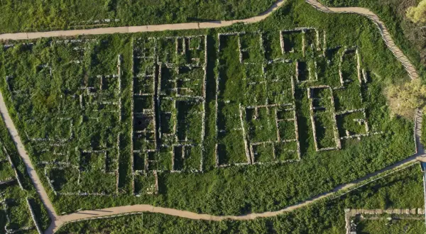 Vista aerea della necropoli centocamere, con rovine antiche immerse nel verde e sentieri che le attraversano.