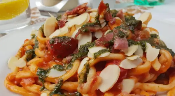 Pasta con pomodoro, pesto, mandorle e pancetta croccante, un piatto da gustare all'enoteca Civita.