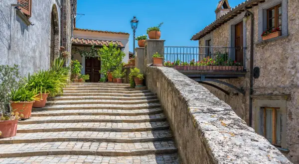 Scalinata acciottolata a Castiglione in Teverina, con vasi di fiori e case in pietra sotto un cielo azzurro.