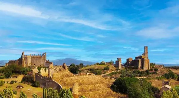 Paesaggio collinare con rovine di castelli e chiese, sotto un cielo azzurro. Un luogo che evoca la storia della riserva naturale di Tuscania.