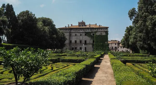 Giardini geometrici e un palazzo storico, il castello Ruspoli a Vignanello, sotto un cielo azzurro.
