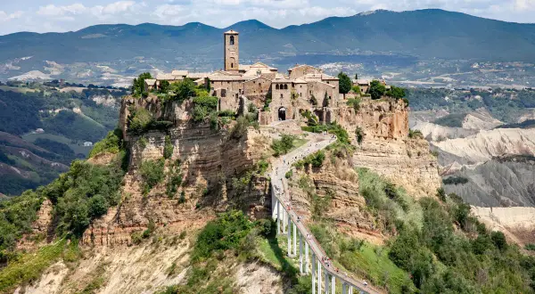 Civita di Bagnoregio, un borgo medievale arroccato su una rupe, raggiungibile tramite un lungo ponte pedonale. La provincia di Viterbo custodisce questo gioiello.