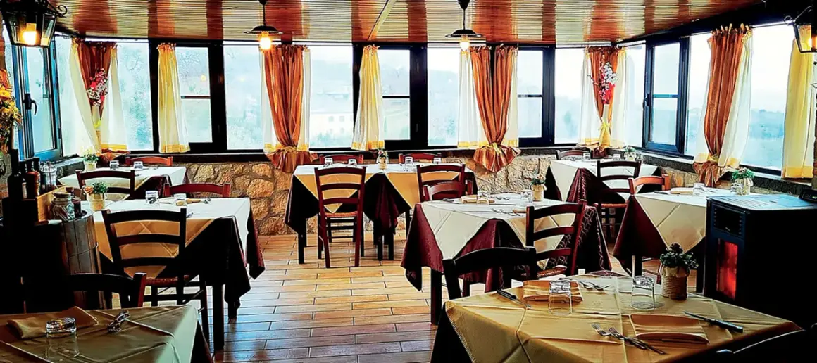 Interno di un'antica cantina a Caprarola, con tavoli apparecchiati e vista panoramica.