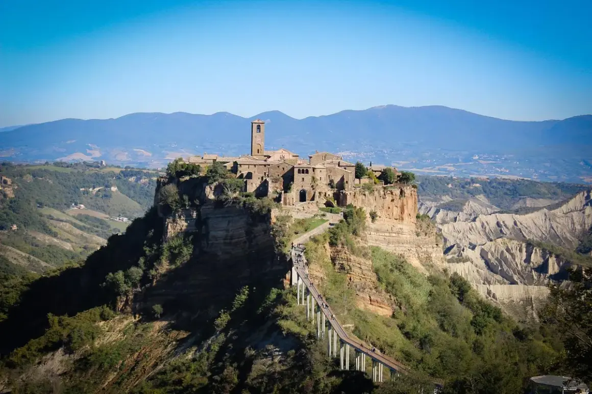 Antica città arroccata su una rupe, con un ponte pedonale che conduce al borgo. Paesaggio mozzafiato di Calcata e dintorni.
