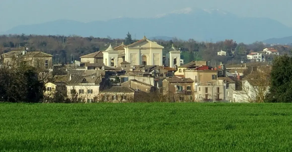 Paesaggio di Gallese, borgo vicino Viterbo, con case e una chiesa imponente, sullo sfondo montagne.