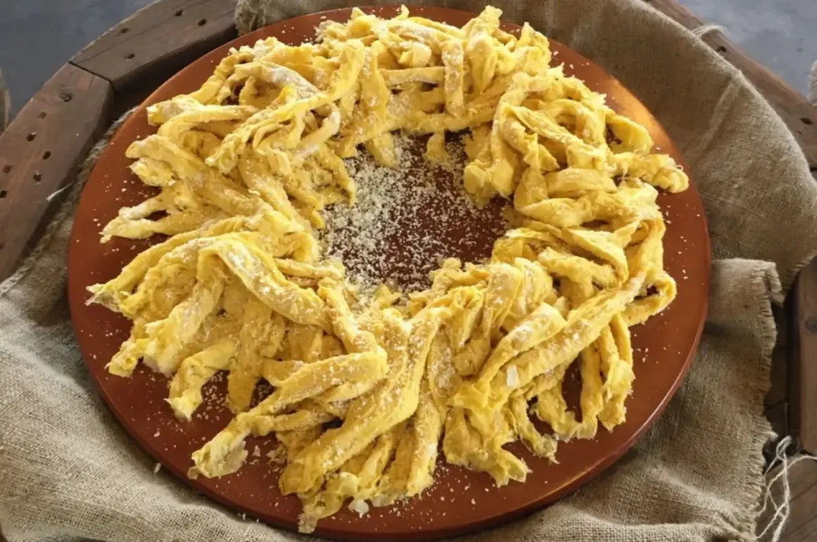 Frittelloni di Civita Castellana, pasta fresca fatta in casa, cosparsa di formaggio grattugiato, disposta a corona su un piatto di terracotta.