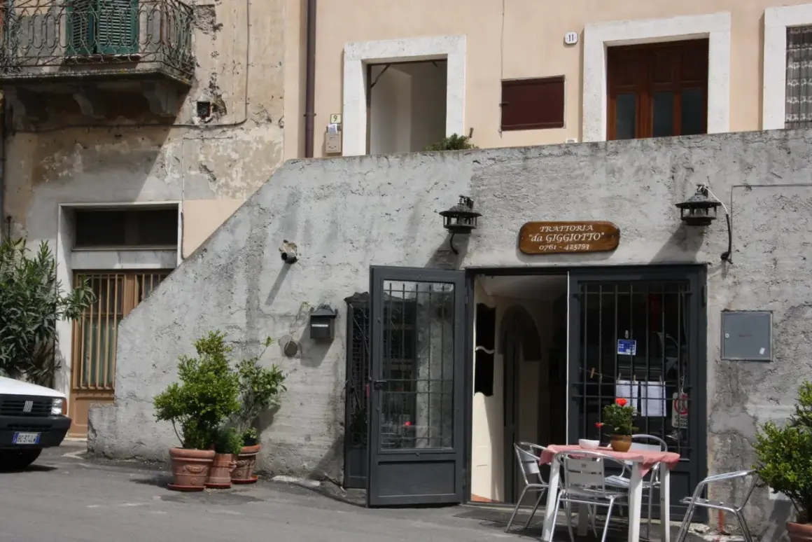 Trattoria "da Giggiotto" a Ischia di Castro, Viterbo. Tavolini all'aperto invitano a gustare i sapori locali.