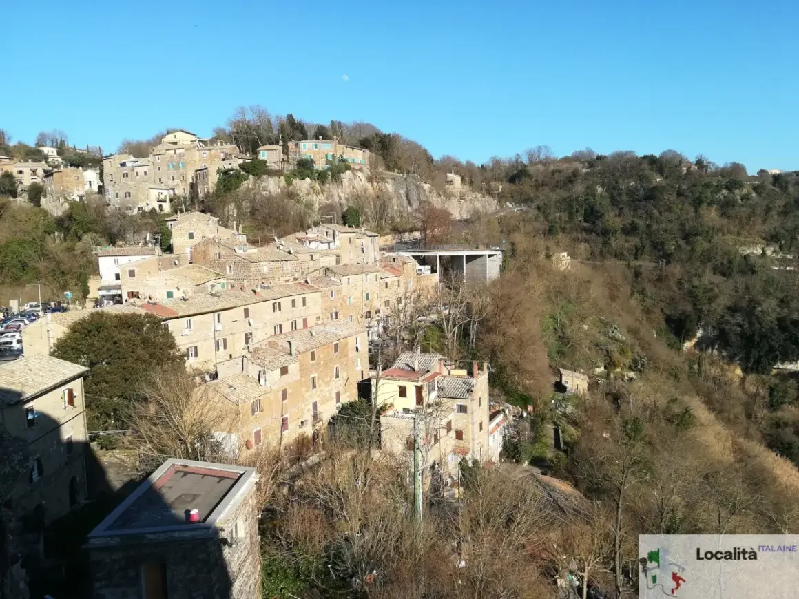 Borgo antico su una collina, con case in pietra e tetti rossi. La **Calcata storia** si svela in questo panorama.