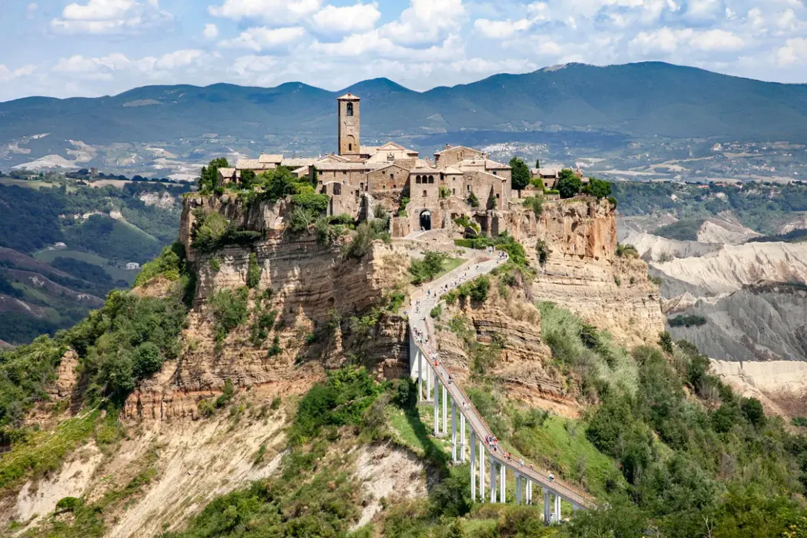 Civita di Bagnoregio, un borgo medievale arroccato su una rupe, raggiungibile tramite un lungo ponte pedonale. La provincia di Viterbo custodisce questo gioiello.