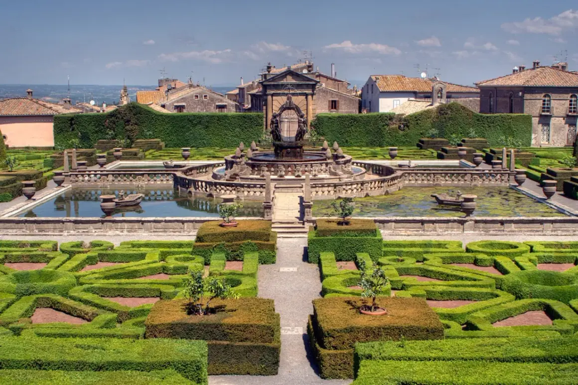 Giardini all'italiana con fontana centrale e siepi geometriche. Si vede il borgo di Bagnaia sullo sfondo.