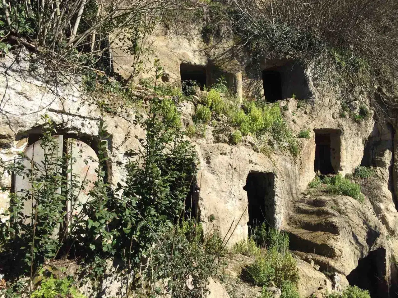 Antiche abitazioni scavate nella roccia, un luogo dove la Calcata storia rivive tra vegetazione e mistero.