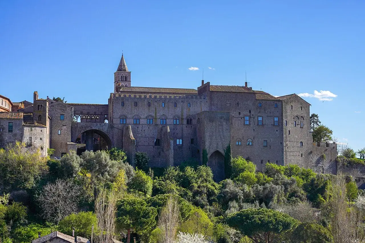 Il maestoso papal palace si erge su una collina verdeggiante, con un campanile a strisce che svetta verso il cielo azzurro.