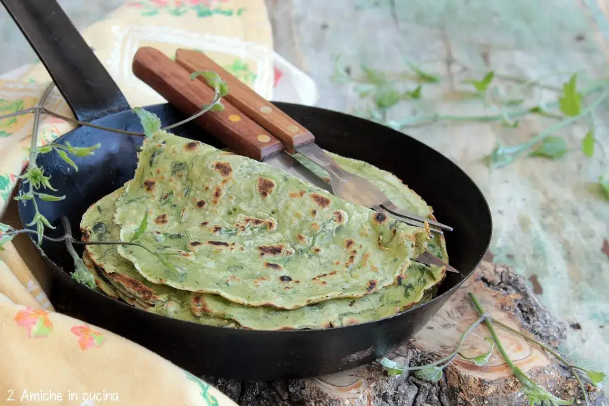 Fregnacce verdi appena fatte, impilate in una padella, con forchetta e coltello.