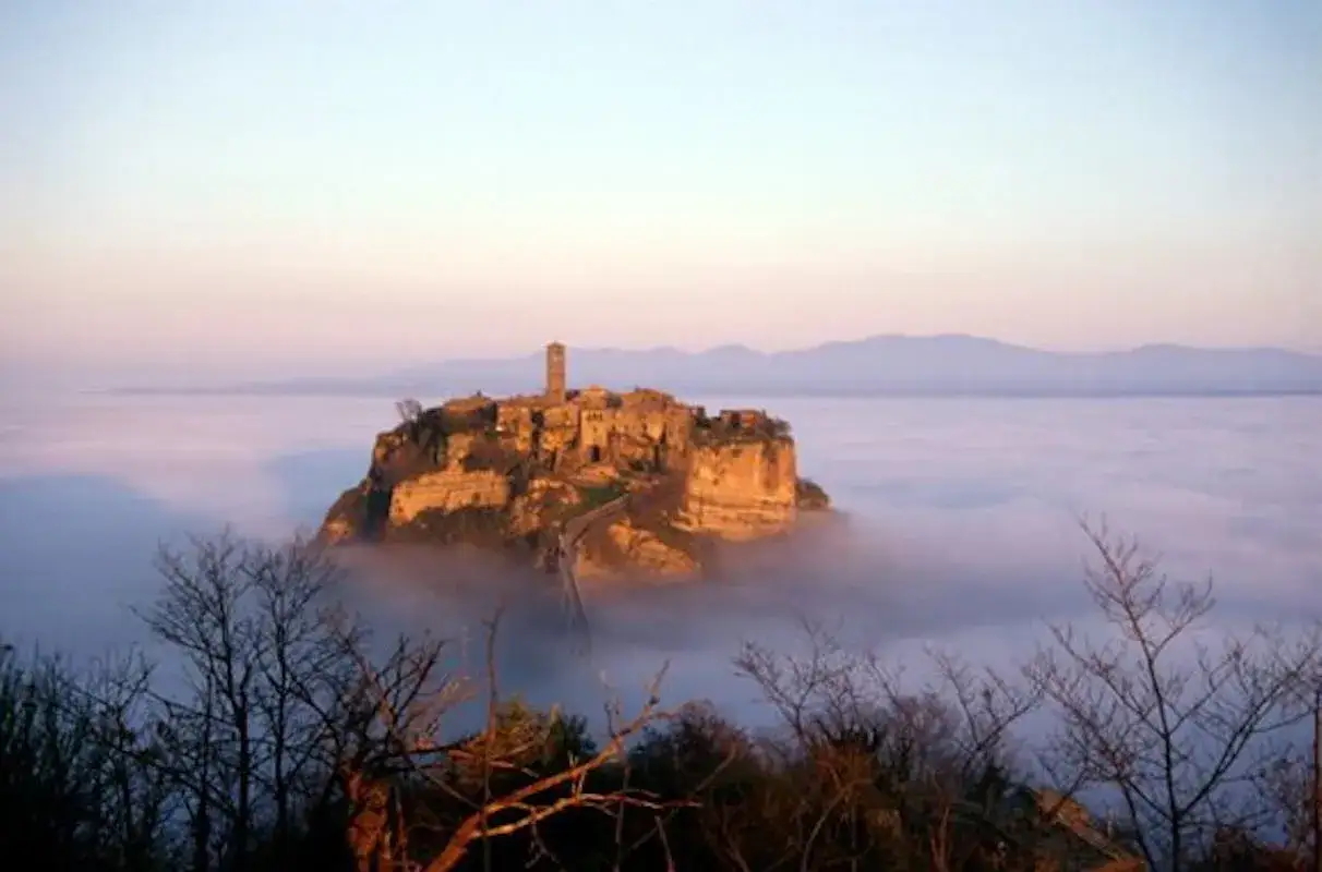 Civita di Bagnoregio, la città che muore, emerge dalla nebbia nella valle dei calanchi, un'isola di roccia e storia.