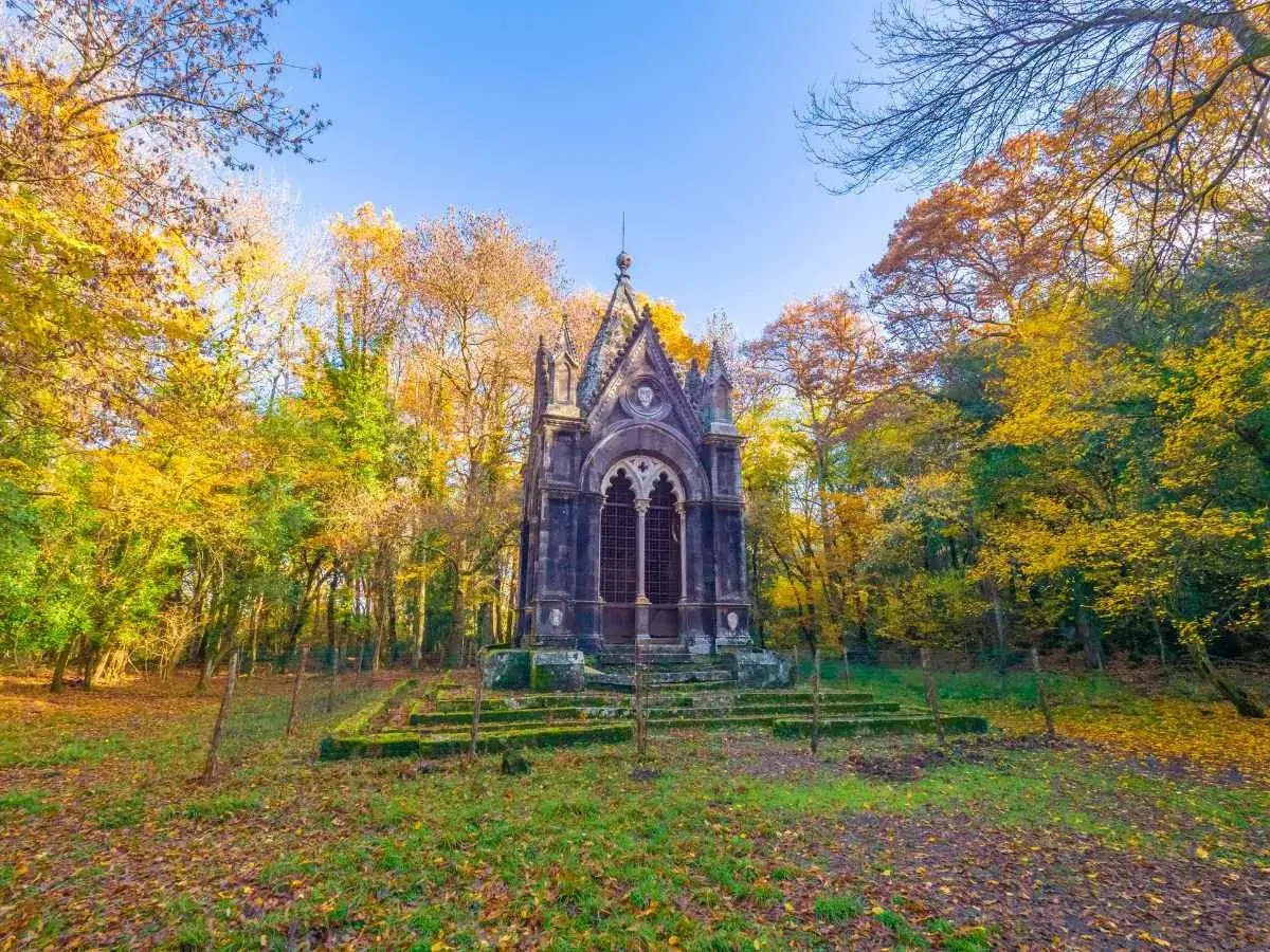 Mausoleo gotico nel bosco del Sasseto, circondato da alberi con foglie autunnali dorate e rosse.