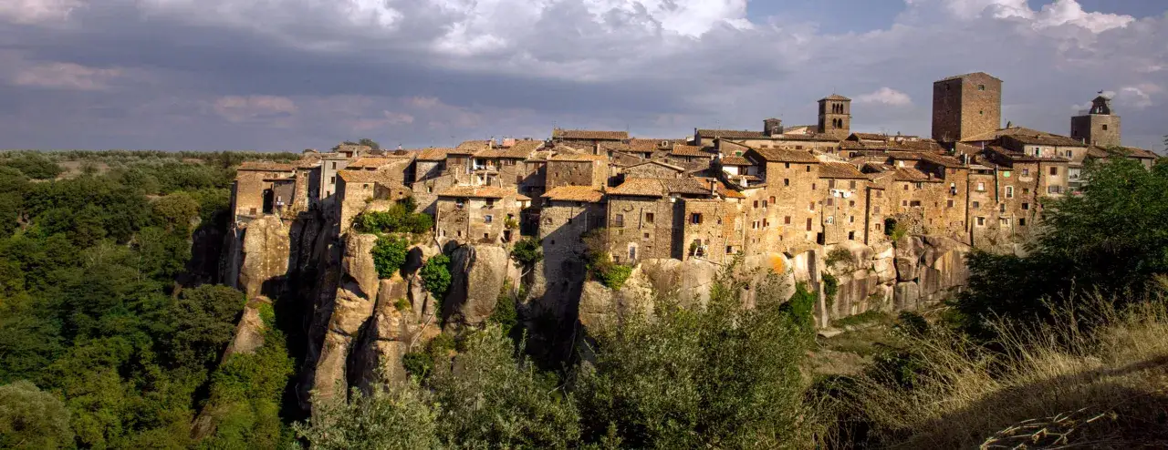 Borgo medievale di Vitorchiano, Viterbo, arroccato su una rupe tufacea, con case in pietra e torri che si stagliano contro un cielo nuvoloso.