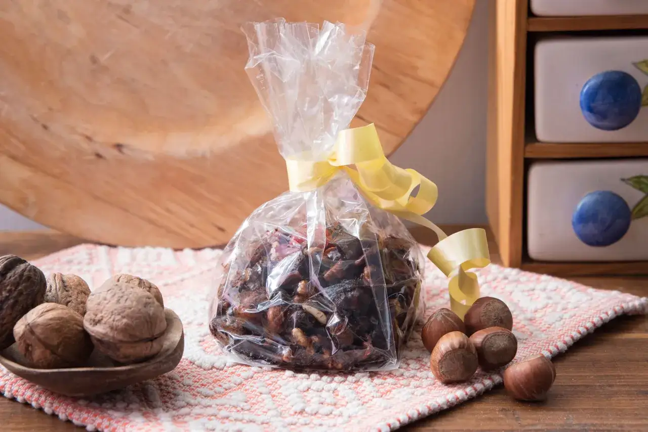 Ingredienti per la pangialli ricetta: noci, nocciole e datteri in un sacchetto trasparente legato con nastro giallo.