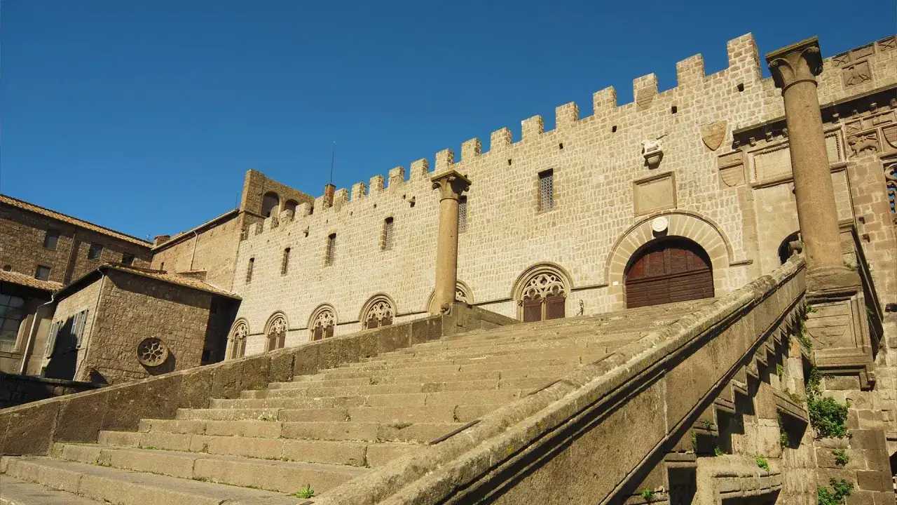Scalinata imponente verso il Palazzo dei Papi in piazza San Lorenzo a Viterbo, con cielo azzurro.