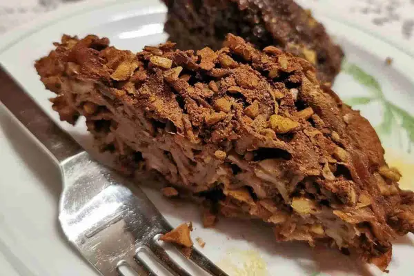 Fetta di torta con strati di pasta e noci, ricoperta di cacao. Un dolce invitante, perfetto per chi ama i maccheroni dolci con le noci.