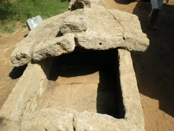 Antica tomba scavata nella roccia, esempio di cosa sono le necropoli. Un riflettore è appoggiato sul bordo.