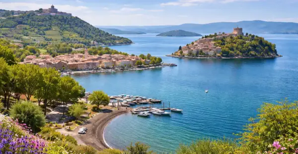 Marta al lago di Bolsena, con borghi pittoreschi, un porto turistico e colline verdi.