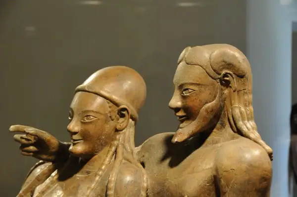 Coppia di statue in terracotta, parte di corredi funerari etruschi. Un uomo indica qualcosa, la donna lo guarda con un sorriso.