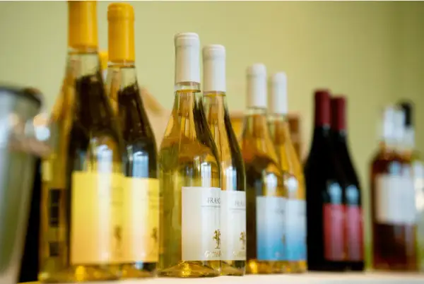 Bottiglie di vini laziali famosi, bianchi e rossi, allineate su uno scaffale, pronte per essere degustate.
