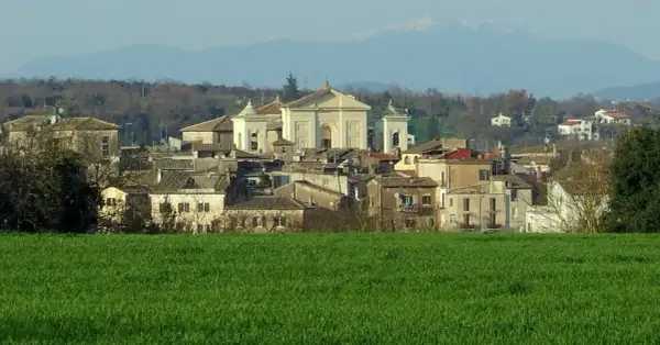 Paesaggio di Gallese, borgo vicino Viterbo, con case e una chiesa imponente, sullo sfondo montagne.