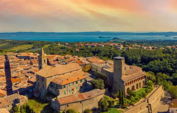 Panoramica di un borgo italiano con un lago sullo sfondo. Scopri cosa vedere a Valentano: un incantevole paesaggio tra storia e natura.