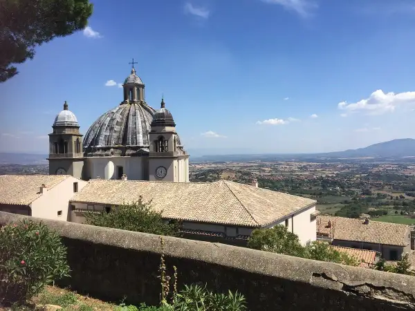 La Rocca dei Papi domina un paesaggio collinare sotto un cielo azzurro.