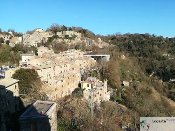 Borgo antico su una collina, con case in pietra e tetti rossi. La **Calcata storia** si svela in questo panorama.