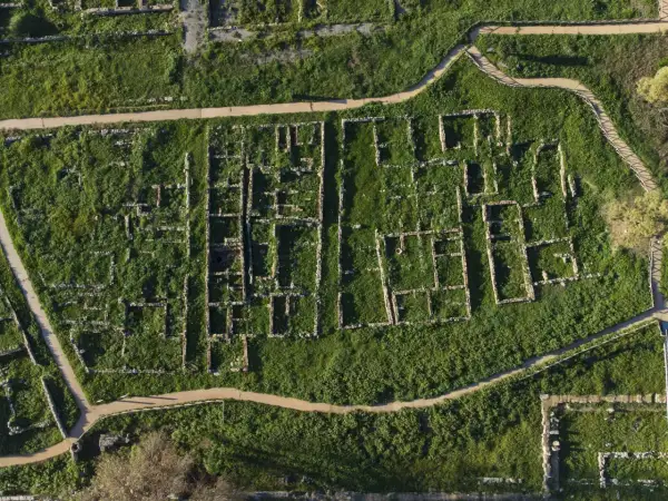 Vista aerea della necropoli centocamere, con rovine antiche immerse nel verde e sentieri che le attraversano.