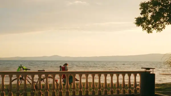 Tramonto sulle spiagge del lago di Bolsena. Una persona in sedia a sdraio, biciclette e un albero creano un'atmosfera serena.