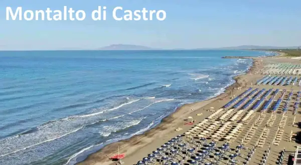 Spiaggia di Montalto di Castro con file ordinate di ombrelloni e lettini, mare azzurro e onde leggere.